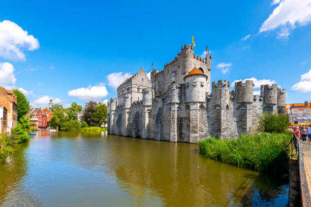 the imposing medieval gravensteen castle along the river lys or leie, in the historic old town district of ghent, belgium. - castle gravensteen imagens e fotografias de stock