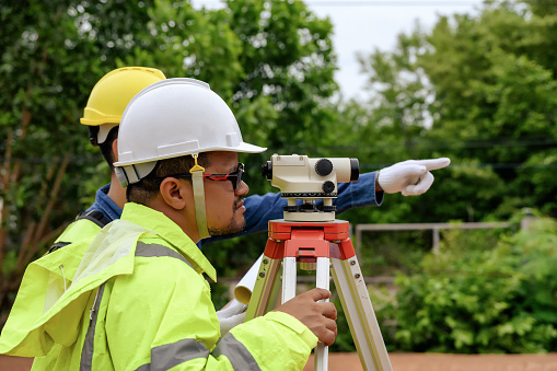 Close-up Asian surveyor engineer using Surveyor's Telescope equipment to measure ground leveling for cut and fill, started leveling the ground at the construction site.