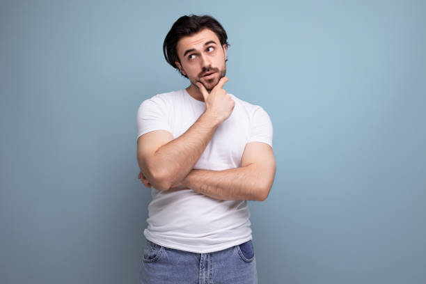 istock young brunette guy in a white t-shirt thought while standing on a studio background 1658007821