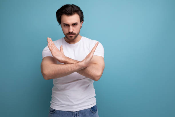 istock bearded brunette guy in white t-shirt shows refusal gesture on studio background with copy space 1658008510