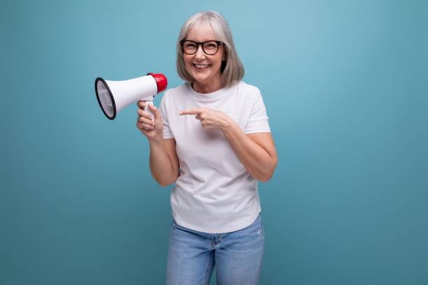 istock a mature woman with gray hair speaks using a megaphone on a studio background 1658009984