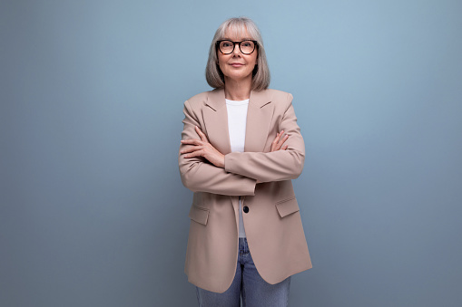 Portrait of happy mature businesswoman standing in the office with her arms crossed and looking at camera. Copy space.
