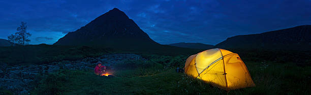 Child toasting marshmallows over wilderness camp fire Child toasting marshmallows over open camp fire beside an illuminated yellow dome tent beneath the silhouetted mountain peaks of Glen Coe, Scotland. ProPhoto RGB profile for maximum color fidelity and gamut. buachaille etive mor photos stock pictures, royalty-free photos & images
