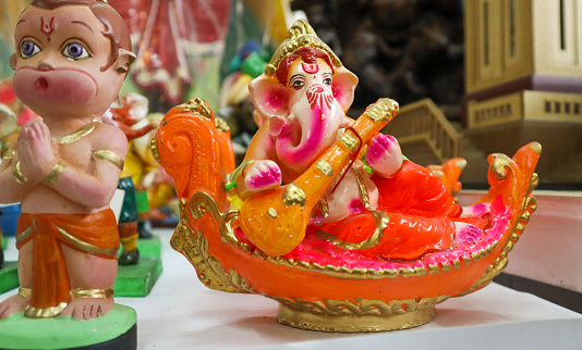Una visión divina de una muñeca o ídolo del Señor Ganesh sentado en un bote cisne y tocando el instrumento de cuerda Veena, es una deidad popular adorada durante los festivales de puja Lakshmi, Diwali, Dasara y Durga puja en la India. photo