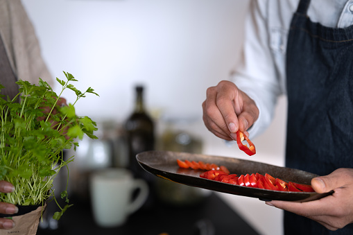 Friends of different races work together to prepare lunch. They cut vegetables, cook spaghetti, goulash, in between they talk and laugh a lot, and in the end they try goulash at the kitchen counter.