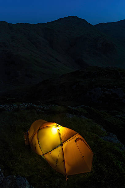 istock Yellow tent illuminated high on dark mountain 165807142