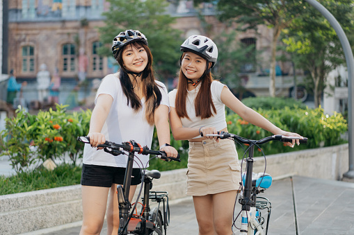 Portrait of two smiling  young Asian Chinese female cyclists in the city