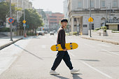 Young asian skateboarder walking on the street