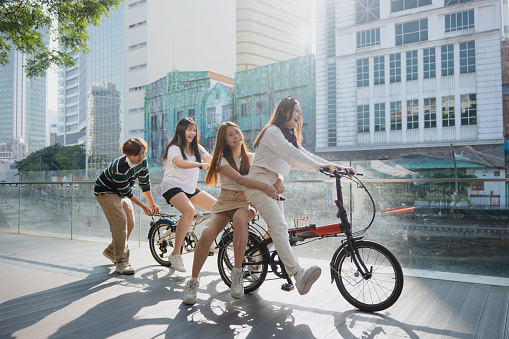 Group of excited young Asian people travel and exploring the city on bicycles