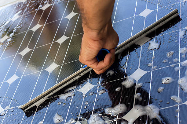 Cleaning solar panel with window cleaner stock photo