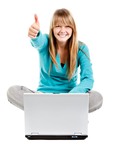 A youthful female sitting with her laptop infront of her. Agreeing with what she has just seen on the screen, she gives the Thumbs Up hand signal. 