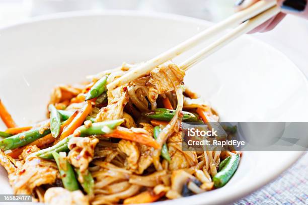 Mano De Mujer Utiliza Le Espera Para Servirlo Pollo Tailandés Plato De Fideos Foto de stock y más banco de imágenes de Sofrito