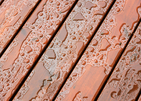 Close-up on the wet surface of protected wooden decking following heavy rain.
