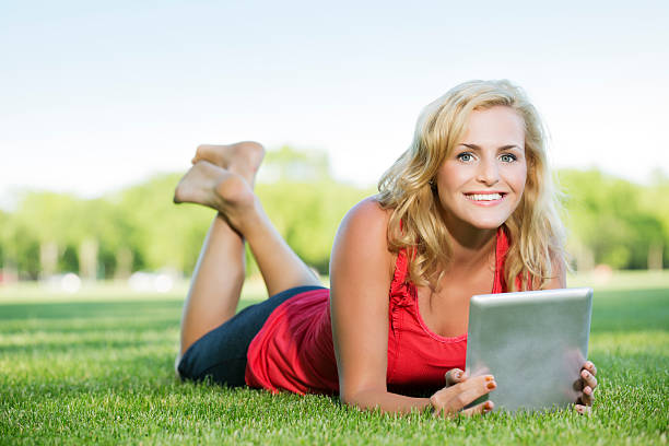 istock Young woman reading something on digital tablet in the park 165827737