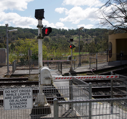 Pedestrian railway crossing with gates closed and red warning lights