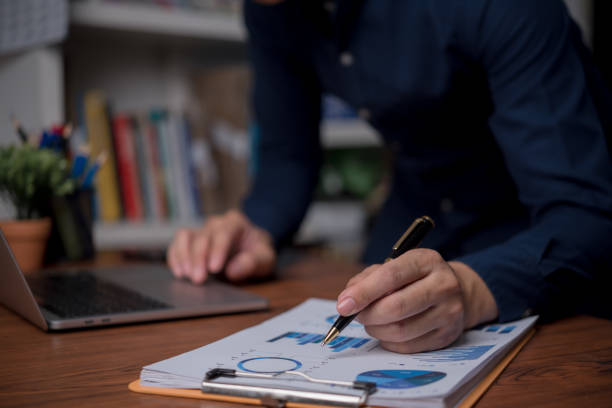 istock Businessman is using a laptop and pointing to a marketing graph working on analyzing financial report company documents, management report online accounting in the office. 1658282945
