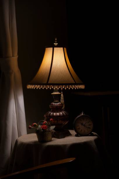 istock Close-up of a small table lamp that illuminated next to a window with a dark background 1658304568