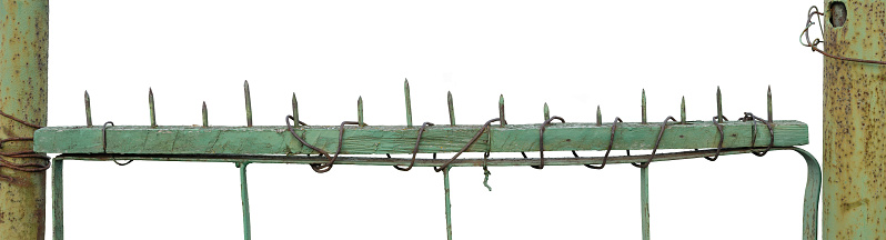 Old aged weathered green painted metallic vintage fence gate, large detailed upward driven nails closeup panorama, isolated horizontal rustic rural kitchen vegetable garden entrance panoramic detail, rusty pole posts, deterrent control security concept, crime deterrence metaphor, grungy abandoned countryside gateway