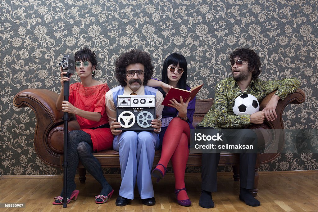 Четырех человек сидит на диване в каждом есть различные Хобби - Стоковые фото 1970-1979 роялти-фри