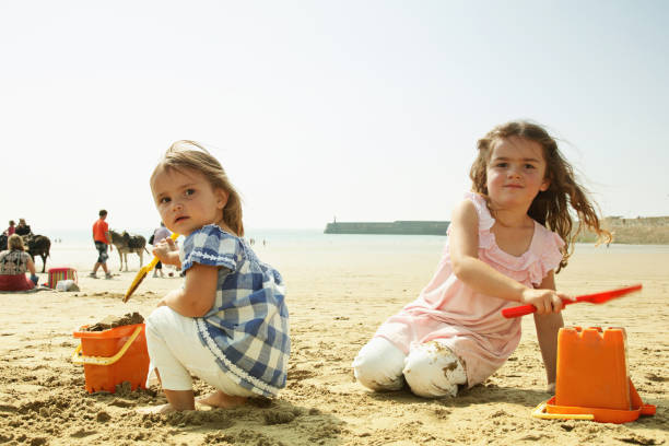 istock Two young girls making sandcastles on the beach 165831359