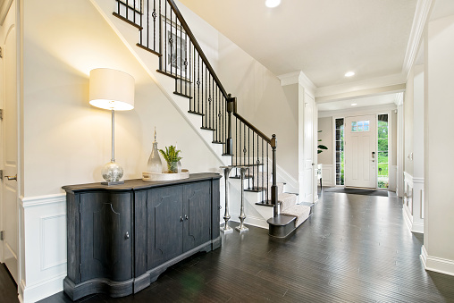 Dark wood flooring and dark wood railing and furniture in contrast to bright white walls and door
