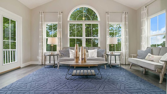 Blue rug and modern furniture with symmetrical lamp shades on each side of the windows