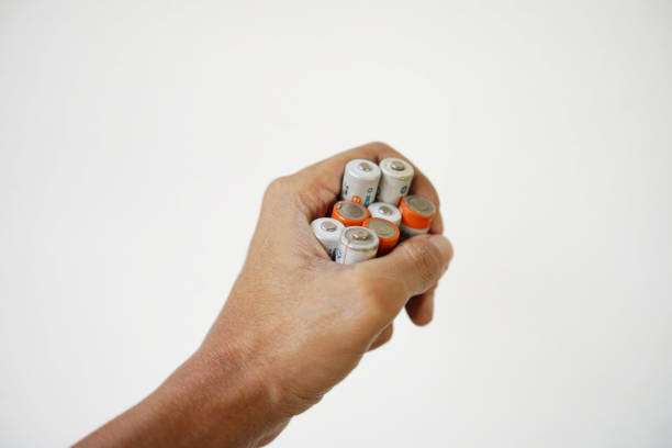asian man's hand holding some used batteries isolated on white background