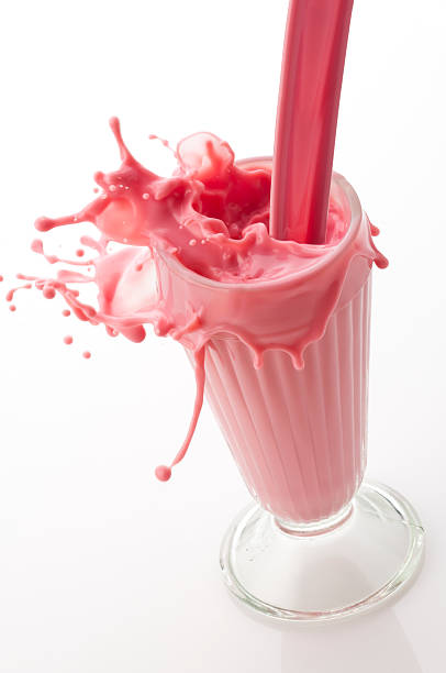 milk-shake à la fraise "être versé dans un verre arborant un splash - cocktail à la fraise photos et images de collection