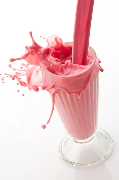 Photo of Strawberry milkshake being poured into a glass showing a splash