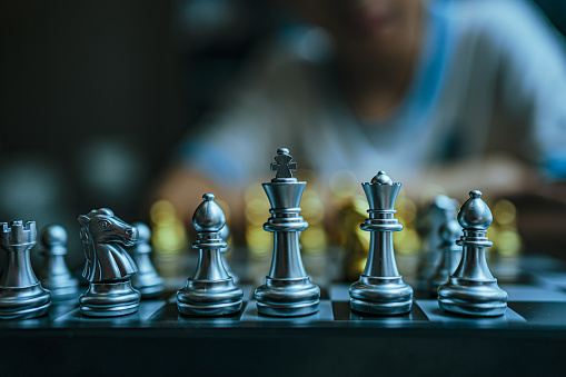 An Asian boy is thinking about how to play chess