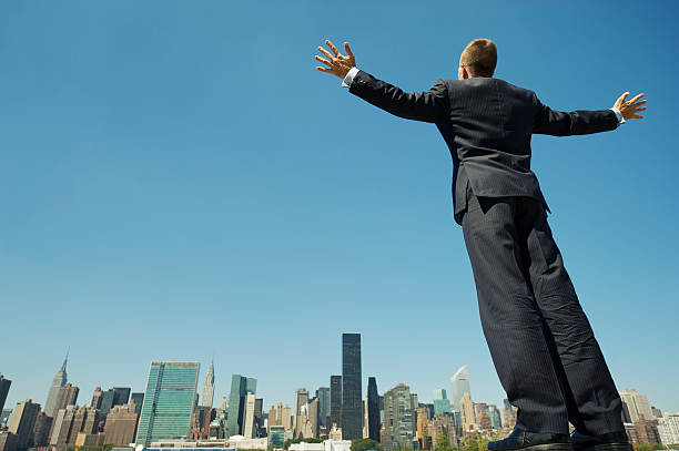 istock Businessman Standing with Arms Spread Above City Skyline 165843347