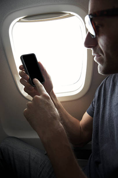 istock Airplane Passenger Using Smart Phone Sitting in Window Seat 165843421