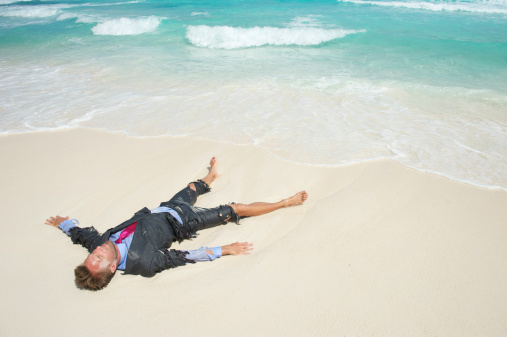 Castaway businessman lies in tattered suit washed up on tropical beach