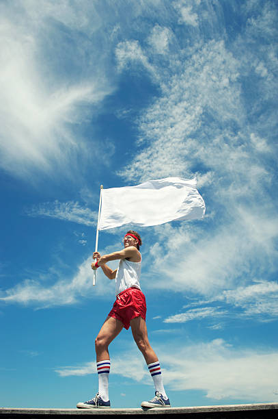 hipster grand dadais athlète agitant fond bleu ciel blanc drapeau en plein air - red flag flag sports flag sports and fitness photos et images de collection