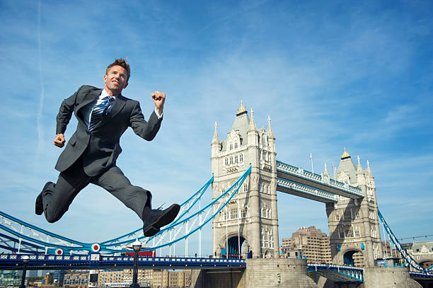 lächelnd geschäftsmann springt über die tower bridge, london - hurdle people england tower bridge stock-fotos und bilder