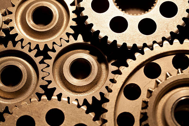 Gears Gears meshing together with gold tint. gear mechanism photos stock pictures, royalty-free photos & images