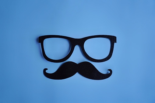 Mustache and glasses on blue background with copy space.  Movember, men's health concept