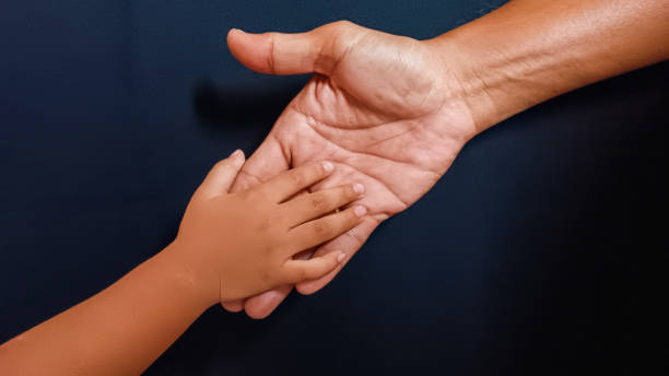 istock Design element of man's father's palm looking after little baby's hand 1658473461