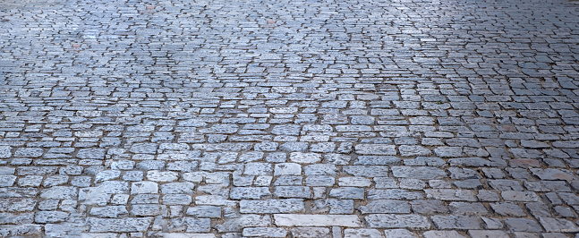 Stone paved footpath, empty cobblestone pathway background texture. Grey paving sidewalk or street for backdrop. Copy space, banner