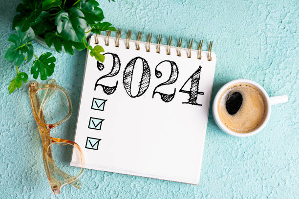 istock New year resolutions 2024 on desk. 2024 goals list with notebook, coffee cup, plant on blue table. Resolutions, plan, goals, action, checklist, idea concept. New Year 2024 resolutions 1658518992