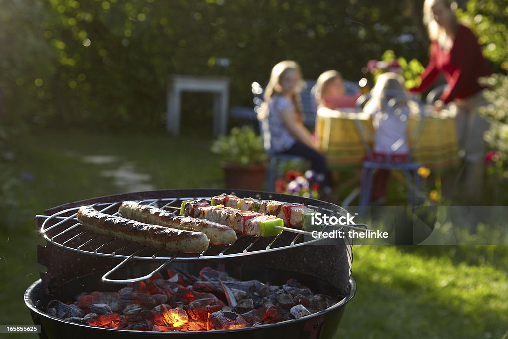 Barbecue grill on a summer evening with family in background Barbecue party on a summer evening. Barbecue Grill Stock Photo