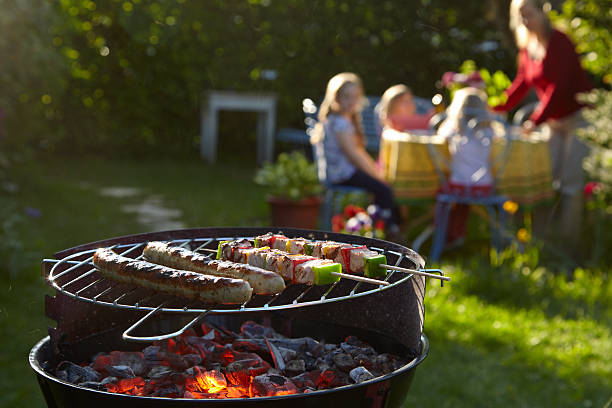 Barbecue grill on a summer evening with family in background stock photo