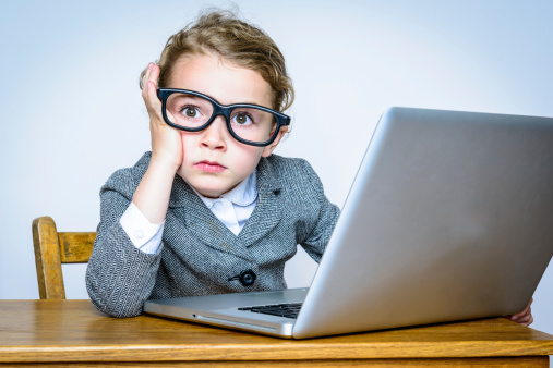 Little girl geek businesswoman bored and exasperated at her computer screen.