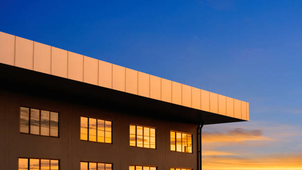 아름다운 일몰 하늘을 배경으로 현대적인 갈색 사무실 건물의 옥상이 있는 유리창 표면에 황금빛 햇빛이 반사되어 있다 - architecture roof aluminum sheet industry 뉴스 사진 이미지