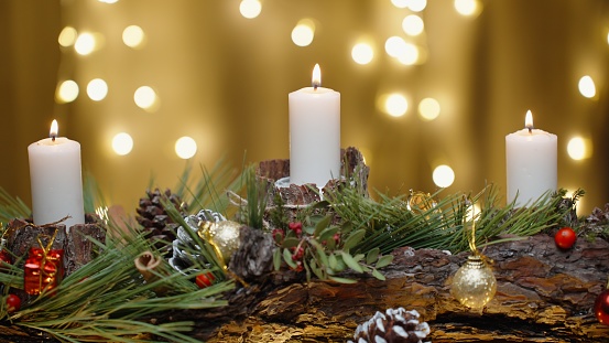 Red Jingle bell glowing in fir tree with Christmas lights on sparkling red background blurred