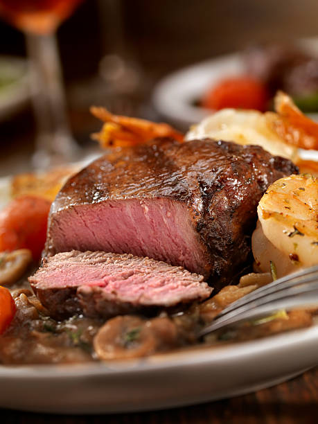 Beef Tenderloin Steak A perfect Medioum Rare Beef Tenderloin Steak with Jumbo Shrimp, Pepper Mushroom Sauce, and roasted Tomatoes -Photographed on Hasselblad H3D2-39mb Camera steak vertical beef meat stock pictures, royalty-free photos & images