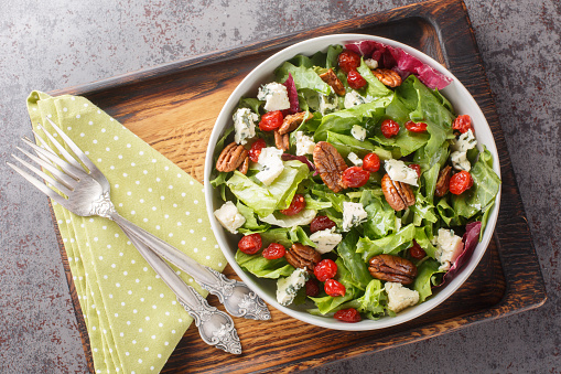 Michigan Cherry Salad with greens, blue cheese and pecan tossed with a vinaigrette dressing closeup on the plate on the table. Horizontal top view from above