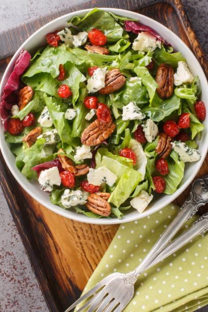 istock Vegetarian salad with leaf lettuce, spinach, arugula, dried cherries, gorgonzola cheese, pecans dressed with vinaigrette sauce close-up in a bowl on the table. Vertical top view 1658588630