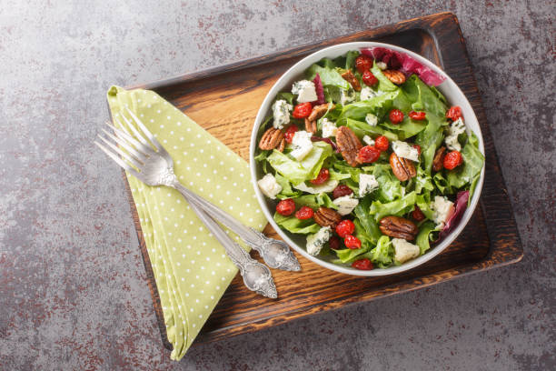 istock Delicious fresh salad with leaf lettuce, dried cherries, gorgonzola cheese, pecans dressed with vinaigrette sauce close-up in a bowl. Horizontal top view 1658590425