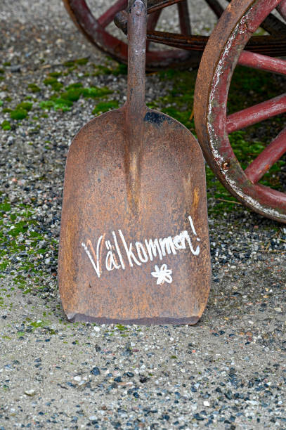 Rusty shovel with the text Welcome in Swedish leaning against an old wagon